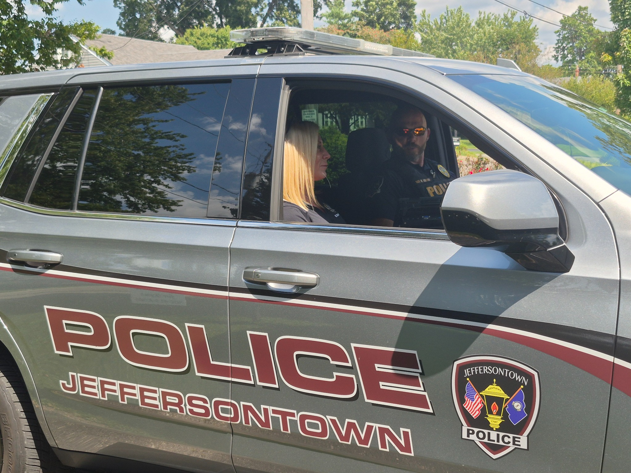A REACH staff member and police officer seated in a Jeffersontown police SUV